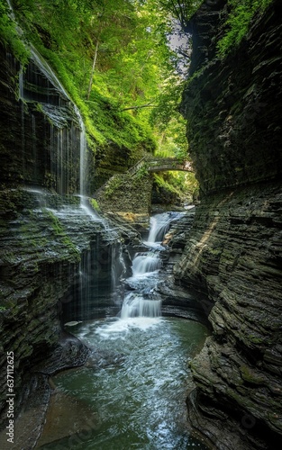 Canvas Print Waterfall cascading through the green forest in the middle of the deep Watkins G
