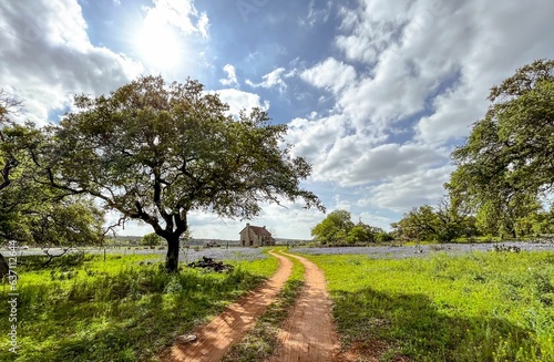 Picturesque country road with a house in the background against rolling hills of Marble Falls, Texas
