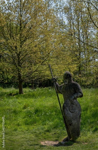 a statue of a woman is standing in the grass holding a spear photo