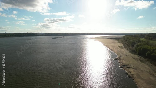 Aerial footage of shiny Mississippi River with trees coast and Memphis Skyline photo