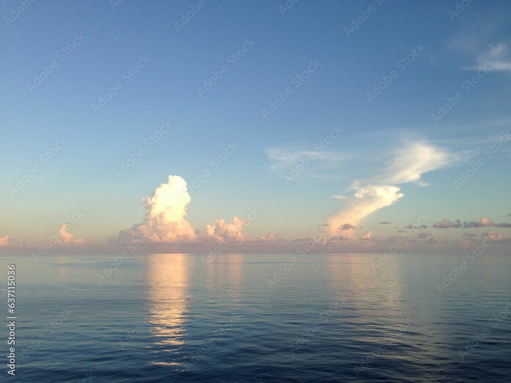 Scenic view of a peaceful ocean, with an expanse of crystal blue water with white clouds