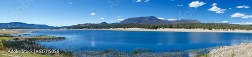 Panoramic view of a lake in a secluded area of the mountains, surrounded by lush green vegetation