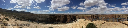 Panoramic shot of an impressive canyon with a vibrant blue sky filled with clouds in the background