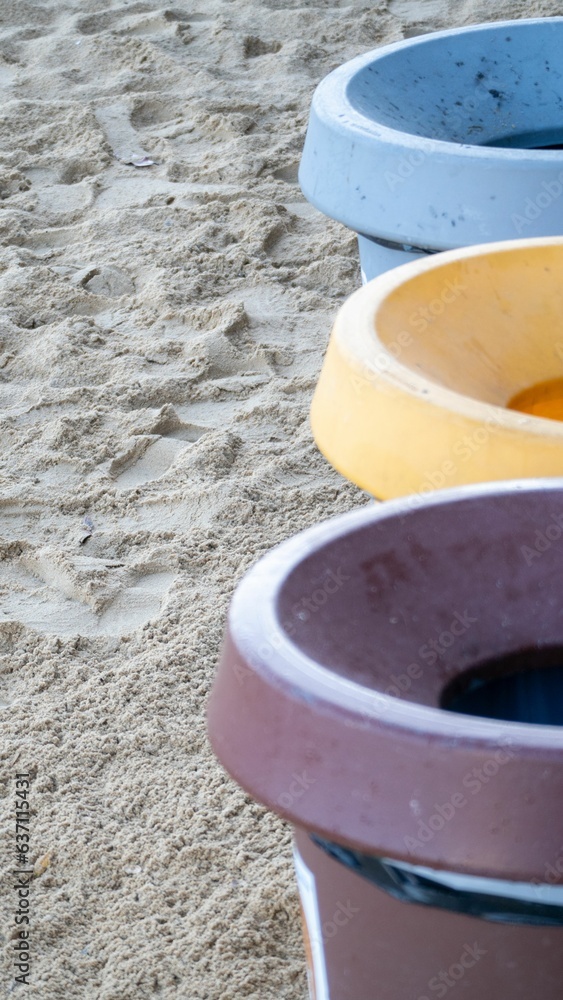 Ceramic pots of various colors are lined up on the beach shore, bathed in sunlight
