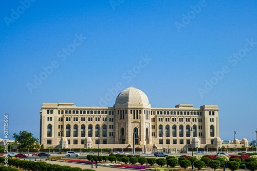 View of the Supreme Court of Oman against a bright blue sky and lush, green gardens