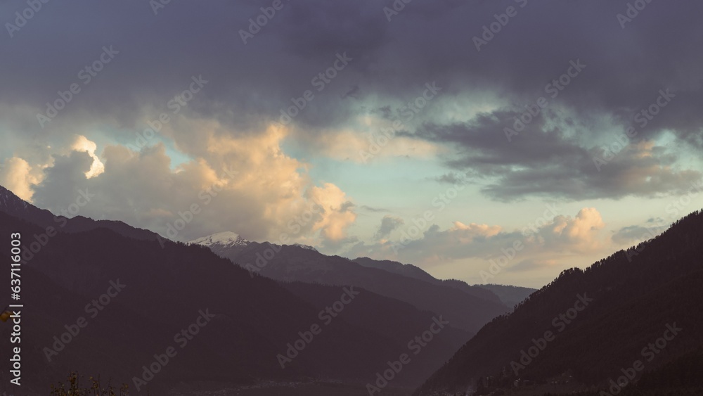 Aerial view of silhouettes of mountains under cloudy sunset sky in Himachal Pradesh, India