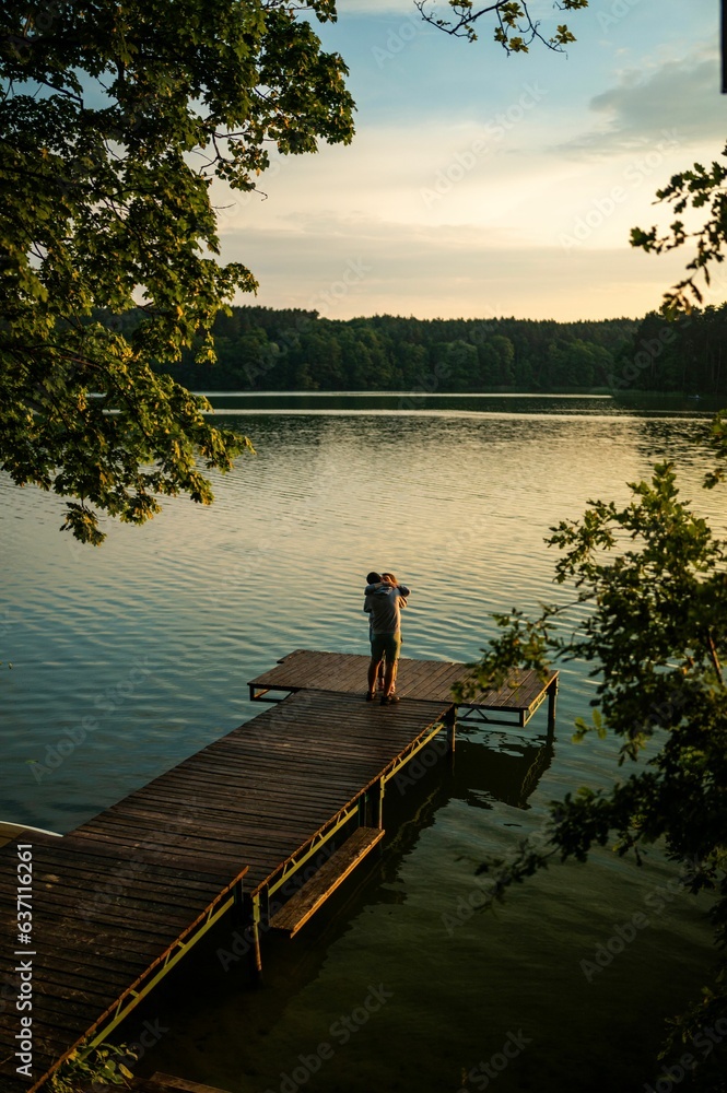 Beautiful couple embracing on a pier overlooking a tranquil lake