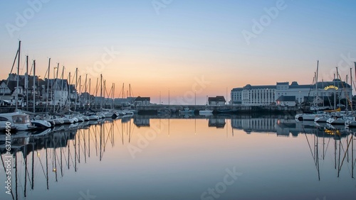 Fleet of vessels moored in a tranquil marina close to a stunning skyline of towering buildings
