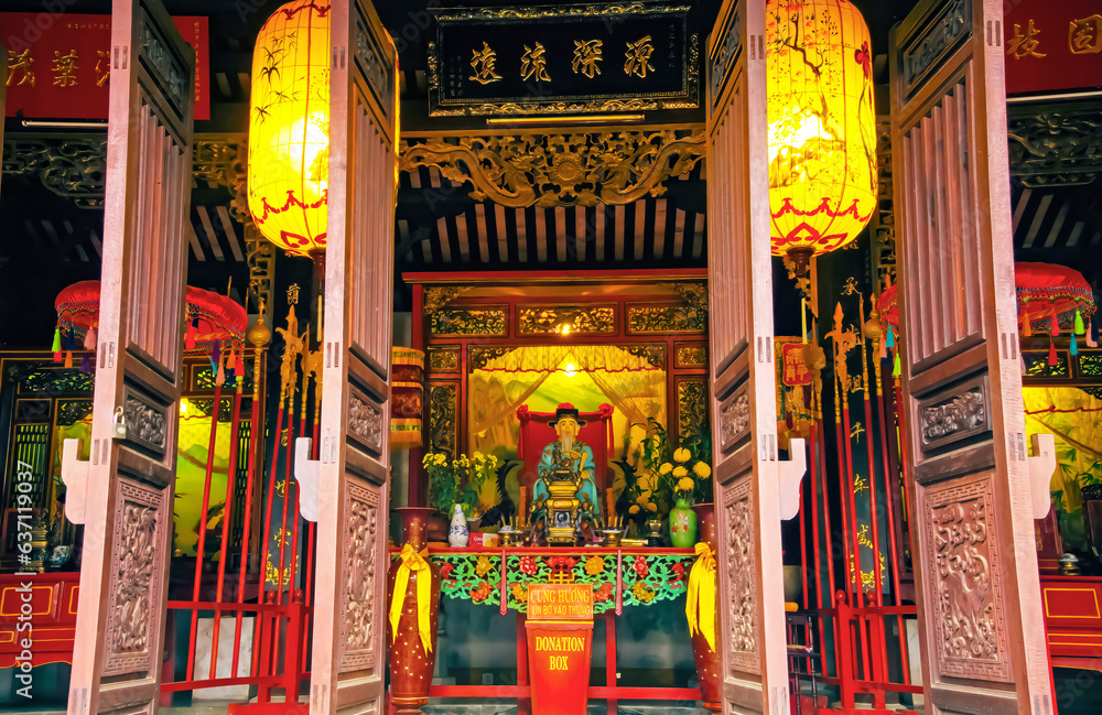 Hoi An (Quan Cong), Vietnam - December 9. 2015: Beautiful temple entrance with symmetric open doors, yellow lanterns, colorful altar