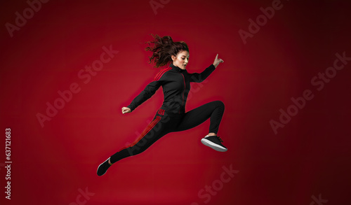 A trendy and athletic dancer jumps on a trampoline in a red studio