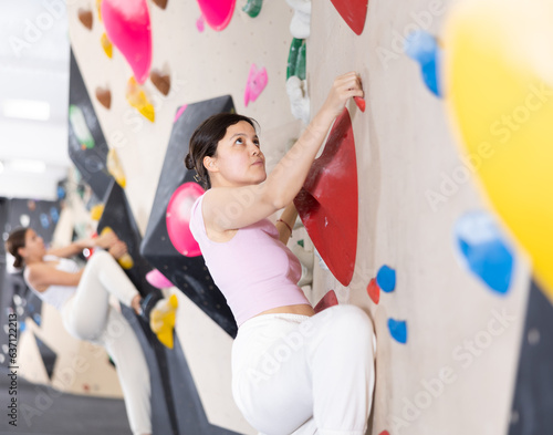 Woman exercising on wall in climbing gym during bouldering training