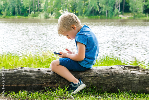 Canvas Print Child boy sits slouching hunched back bent,neck,looks phone,over device