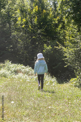 Adorable little girl hiking in the forest, spending time in the nature, outdoors experience in the countryside