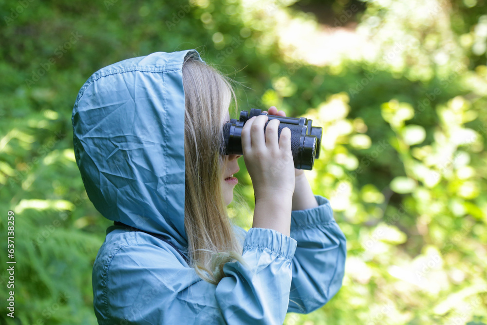 Cute little girl exploring nature looking through binoculars. Child playing outdoors. Kids travel, adventure and bird watching concept. Cute little girl exploring nature looking through binoculars. Child playing outdoors. Kids travel, adventure and bird watching concept.