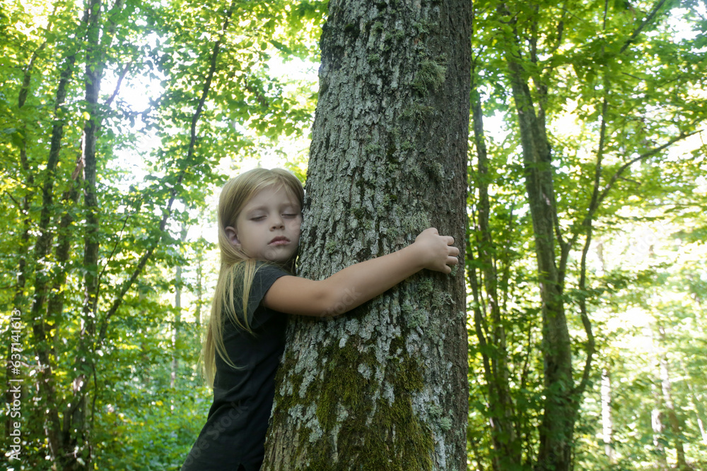 Cute little girl hugging tree. Hugging and touching trees provide rich sensory experience for children, reduce stress, improve immunity, lower blood pressure, accelerate recovery from trauma Cute little girl hugging tree. Hugging and touching trees provide rich sensory experience for children, reduce stress, improve immunity, lower blood pressure, accelerate recovery from trauma