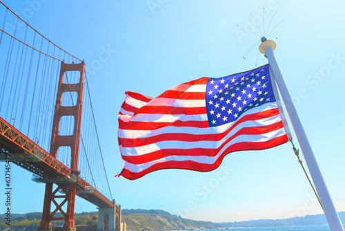 The Golden Gate Bridge from the Box of a boat below the Bridge with the US Flag flying off the bow.