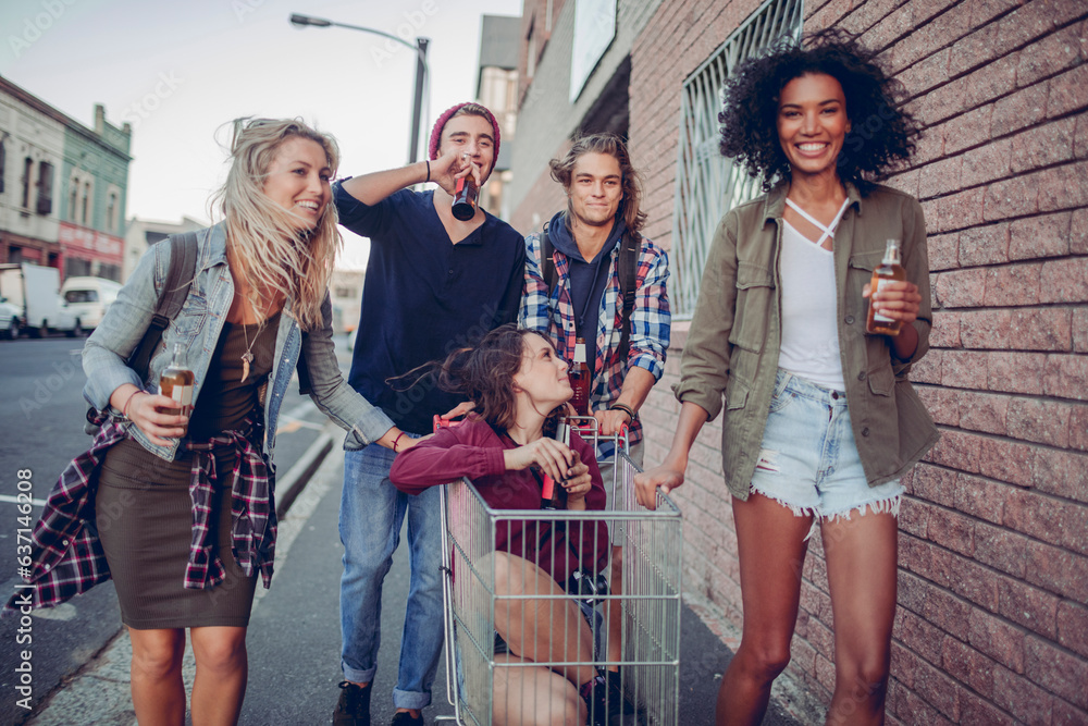 © Marko Geber - Diverse group of young people having a beer and having fun with a shopping cart on a city sidewalk