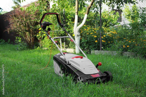 Lawn mower on green grass in garden