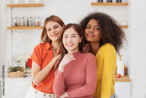 Portrait three beautiful LGBT lesbian couple in colorful shirts  happy in kitchen at home spending time cooking together  multiracial lesbian couple living proud  charming smile looking at camera.