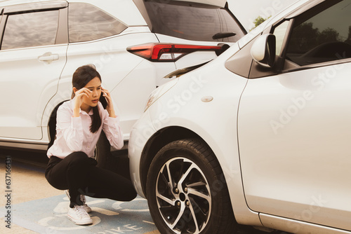 Asian woman sits stressed and worried as her reckless driver hits the back of her car and damages the front. Sit and use your smartphone to call your insurance company for help with repairs. © ฺฺฺBoonterm