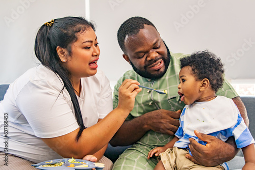 Happy multiracial family, african american dad and asian mom in good mood healthy lifestyle with a cute half-Thai-Nigerian son andmother holding tray of easy to digest food for her son for lunch.
