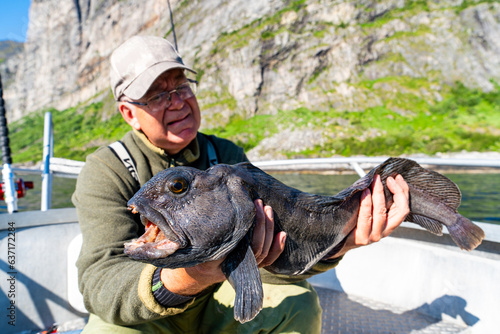 Fisherman with big wolffish on the boat near Lofoten, Senija, Alta - Norway. Man holding catch Atlantic wolf fish photo