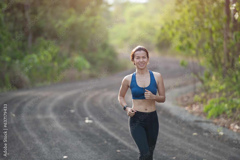 young fitness woman runner athlete running at road. athlete woman in running start pose on countryside street. sport tight clothes. bright sunset, Healthy woman on morning road workout jogging. young fitness woman runner athlete running at road. athlete woman in running start pose on countryside street. sport tight clothes. bright sunset, Healthy woman on morning road workout jogging.