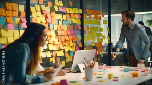 A man and woman team organizing and analyzing sticky notes on a wall in a modern office