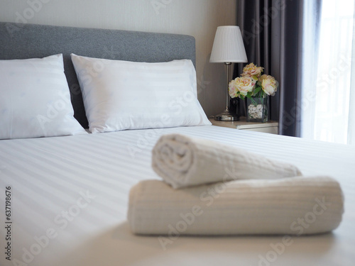 White soft pillows on the neatly clean bed with blurred foreground of baht towels - home , coziness and clean concept 