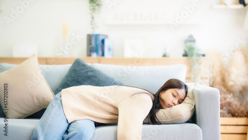 Asian woman resting at home on couch, feeling exhausted after work, lacking energy, or overworked, too tired, and lacking motivation