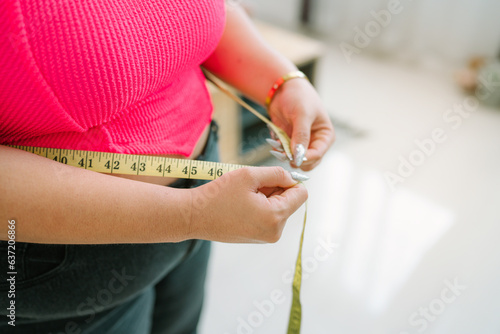 Fat Asian woman want to lose weight with a centimeter Shape up healthy stomach muscle and diet measuring waist with measure tape after diet weight control.