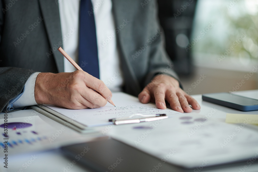 Hands of senior entrepreneur taking notes when analyzing data in reports Hands of senior entrepreneur taking notes when analyzing data in reports