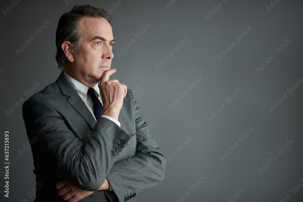Studio portrait of pensive businessman in formalwear rubbing chin and looking away Studio portrait of pensive businessman in formalwear rubbing chin and looking away