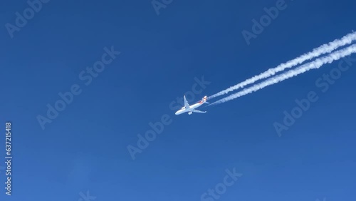 A massive  white Airbus 330 jet and its wake  shot from the cabin of another jet flying bellow. photo