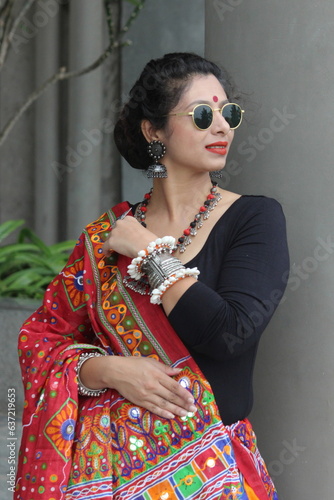 Indian woman in a stylish traditional look for Navratri for playing Garba and dandiya wirh sun glasses and fabric and oxidized jewelry. red and black outfit with traitional bangles earings, bindi. photo