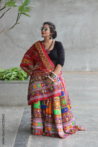 beautiful indian woman wearing red and black chaniya choli with multicolor ghaghra and fabric jewelry. Outfit for garba and dandiya in navratri festival. folk dance of gujarat india celebrated across photo