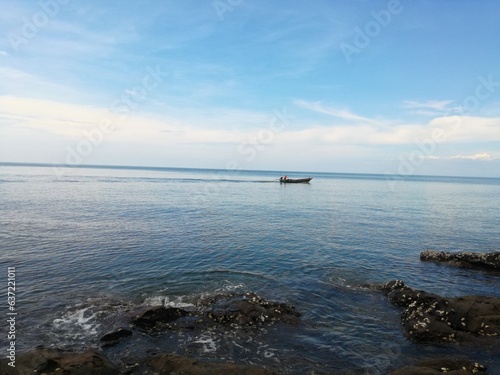 Seascape rocks on sea with boat and blue sky
