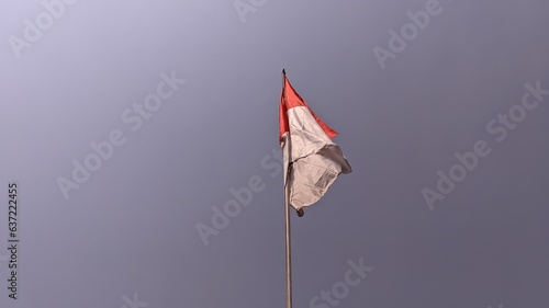 The red and white Indonesian flag flutters against a blue sky background