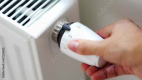 A woman's hand turns the battery heating knob. Heating in an apartment, at home. Heating prices. photo