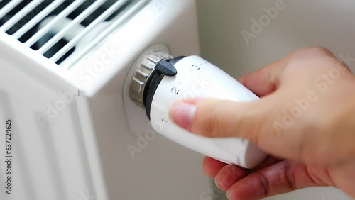 A woman's hand turns the battery heating knob. Heating in an apartment, at home. Heating prices.