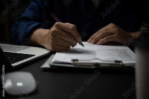 Male hand holding a pen to write a document or sign a business or legal contract. Checklist of financial documents and market reports