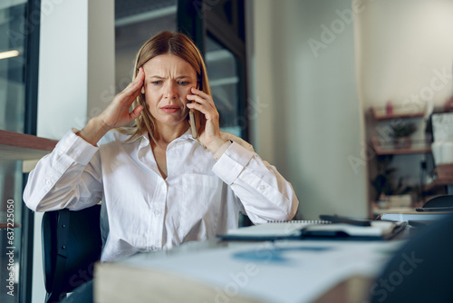 Obraz na płótnie Worried woman manager makes business call and listens client claim while sitting