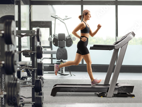 Profile shot of a fit strong woman running on a treadmill