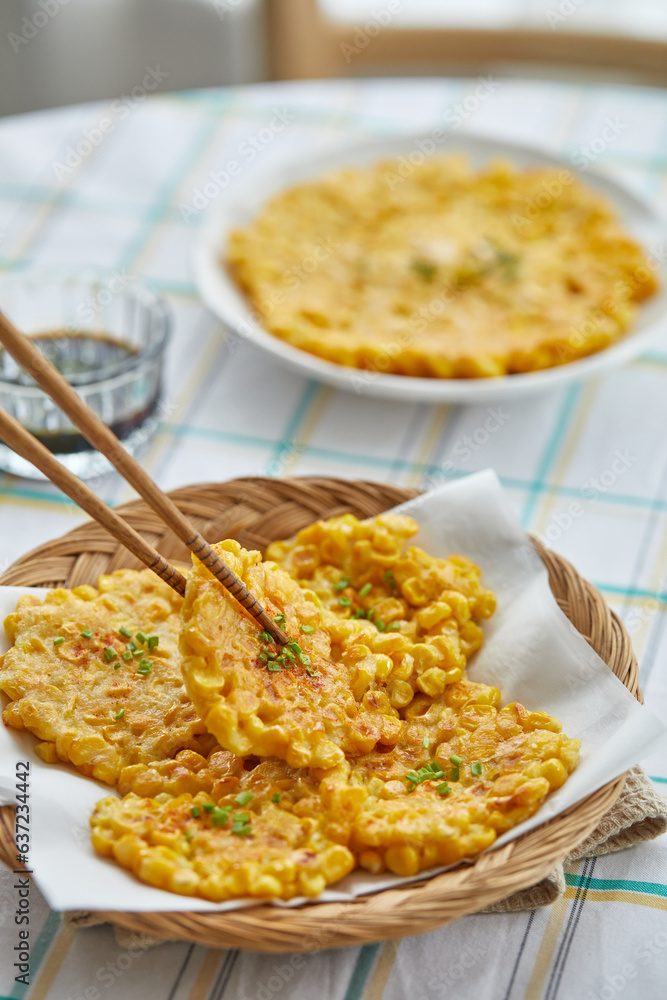 테이블 위에 맛있게 만들어진 찰옥수수전을 젓가락으로 한개 집어올리고 있는 모습 테이블 위에 맛있게 만들어진 찰옥수수전을 젓가락으로 한개 집어올리고 있는 모습