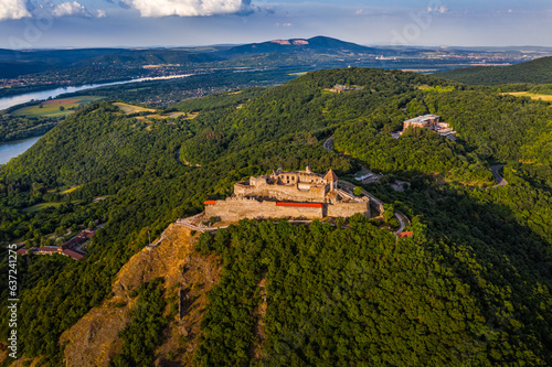 Visegrad, Hungary - Aerial drone view of the beautiful high castle of Visegrad with summer foliage and trees. Dunakanyar and blue sky with clouds at background on a sunny day photo