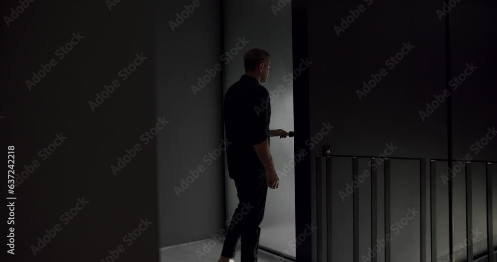 The man opens the transparent door and close it in the modern house and creates silhouettes and shadows. modern interior design with gray colors. Minimalist design Interior in black and gray colors. The man opens the transparent door and close it in the modern house and creates silhouettes and shadows. modern interior design with gray colors. Minimalist design Interior in black and gray colors.