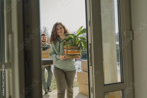 Happy woman carrying houseplant into new home