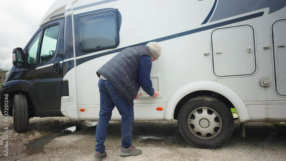 A man pulls a toilet waste container out of a caravan A man pulls a toilet waste container out of a caravan