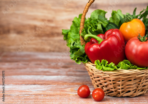 Fresh vegetables and greens in a wicker basket on a wooden background. Harvesting. Thanksgiving Day. Copy space.