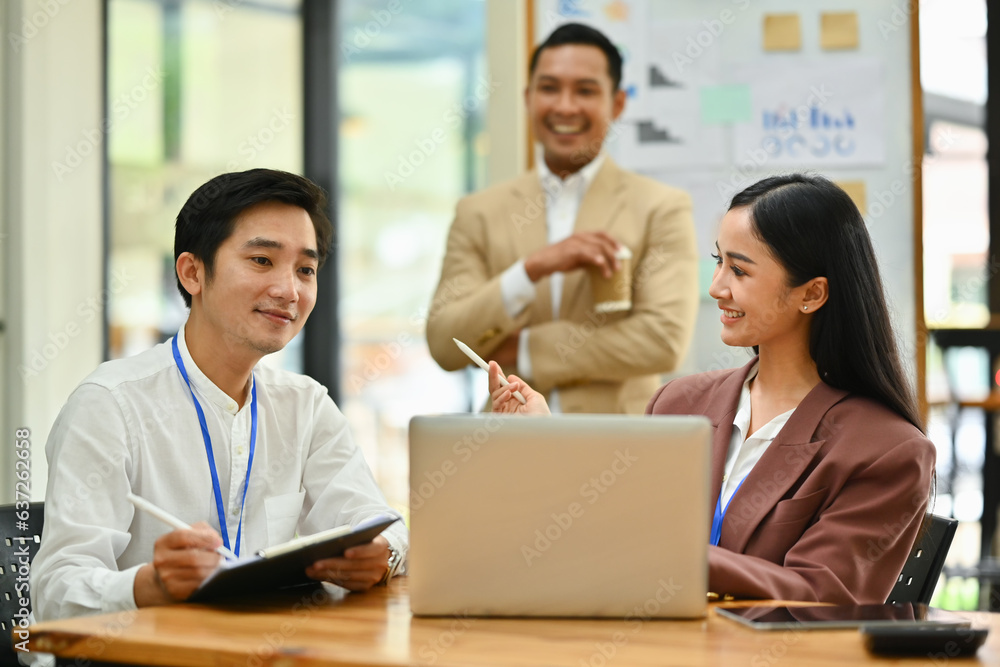 Business team looking at laptop screen, brainstorming for important project in modern corporate office Business team looking at laptop screen, brainstorming for important project in modern corporate office